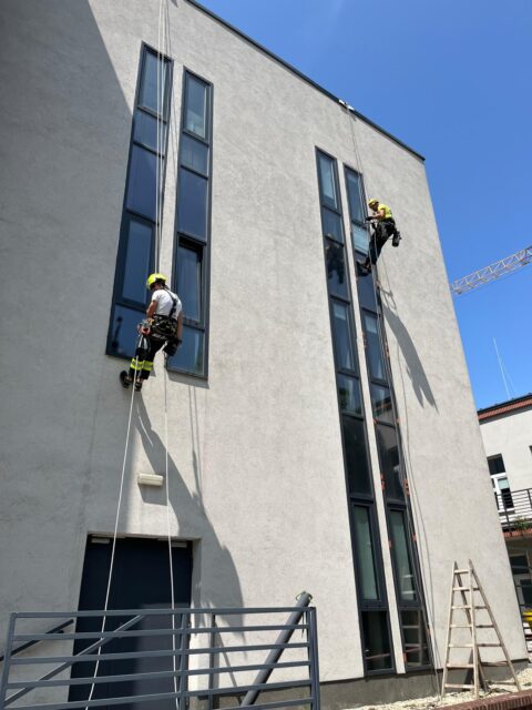 Dwóch alpinistów na elewacji budynku wykonuje prace na wysokości